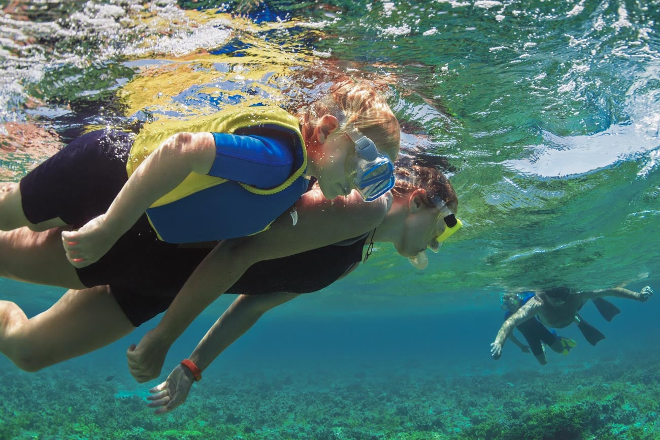 Happy family - father, mother, kids in snorkeling mask dive underwater with tropical fishes in coral reef sea pool. Travel lifestyle, watersport adventure, swimming on summer beach holiday with child.